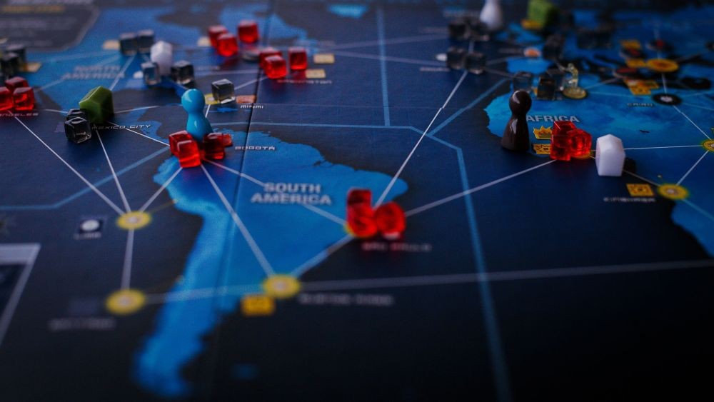 Pandemic board game map with colorful player tokens and red cubes