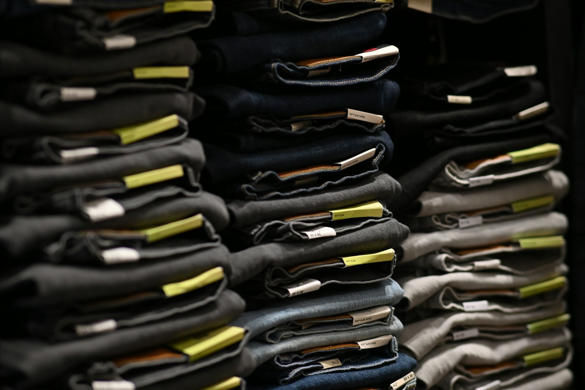 Stacks of denim jeans with quality control tracking tags, illustrating garment inventory management and inspection readiness.
